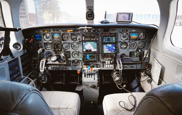 Interior view of an airplane cockpit, showcasing a complex array of controls, instruments, and navigation equipment used by pilots to manage and navigate the aircraft.