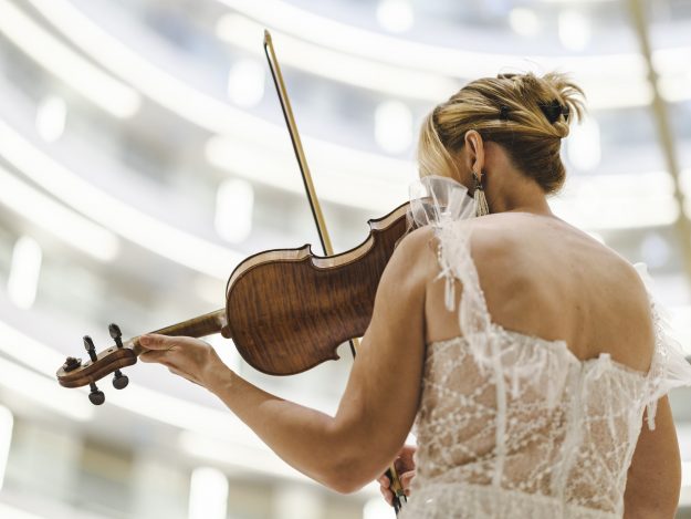 A woman playing the violin with precision and grace, symbolizing the harmony and skill involved in retaining key talent during M&A integration.