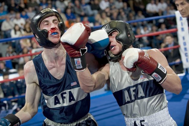 Boxing match representing the struggle of keeping an acquired brand versus unifying under a single brand in M&A.