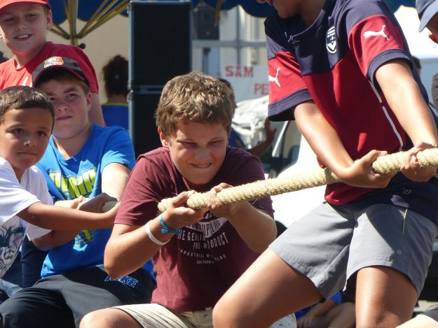 Children in a tug-of-war game symbolizing the strategic tension in deciding to retain an acquired brand in SME and mid-market M&A.