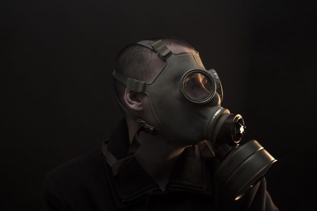 A man wearing a gas mask, facing sideways in a dark environment—symbolizing the unseen risks and harsh realities CEOs face in private equity-backed buy-and-build strategies. Featured image for the blog titled "Blindsided: Why Most CEOs Fail in Buy-and-Build."