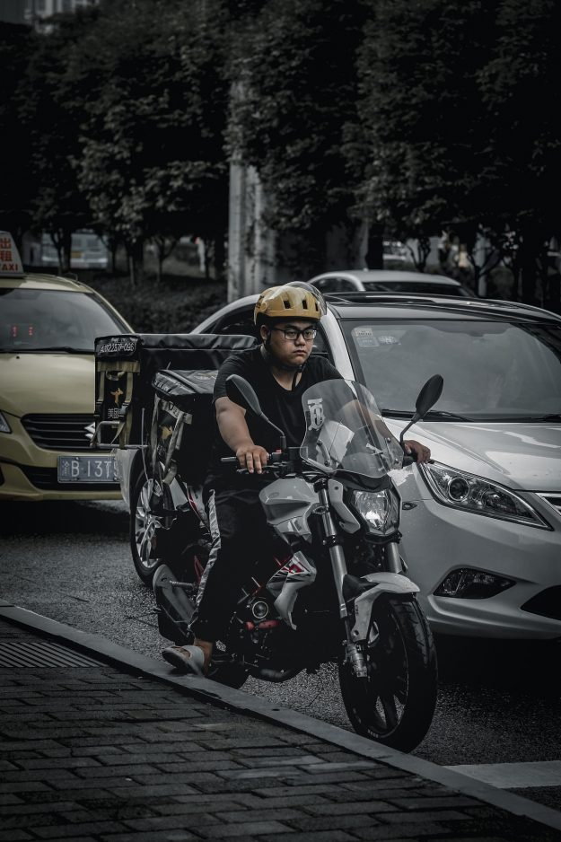 A delivery rider weaving through city traffic, representing the human face of platform logistics—featured in the article ‘DoorDash–Deliveroo Merger: Will Integration Deliver?’ which explores the strategic risks, cultural hurdles, and leadership alignment needed for successful integration.