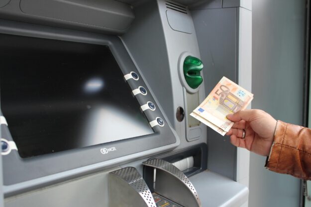Growth Doesn’t Fund Itself: What Scaling Costs an Owner-Led Business – hand holding 50-euro notes beside an ATM